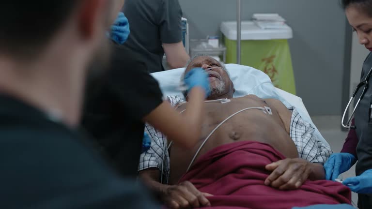 A modern trauma bay: an elderly patient on a gurney with EKG leads, attended by a gloved team